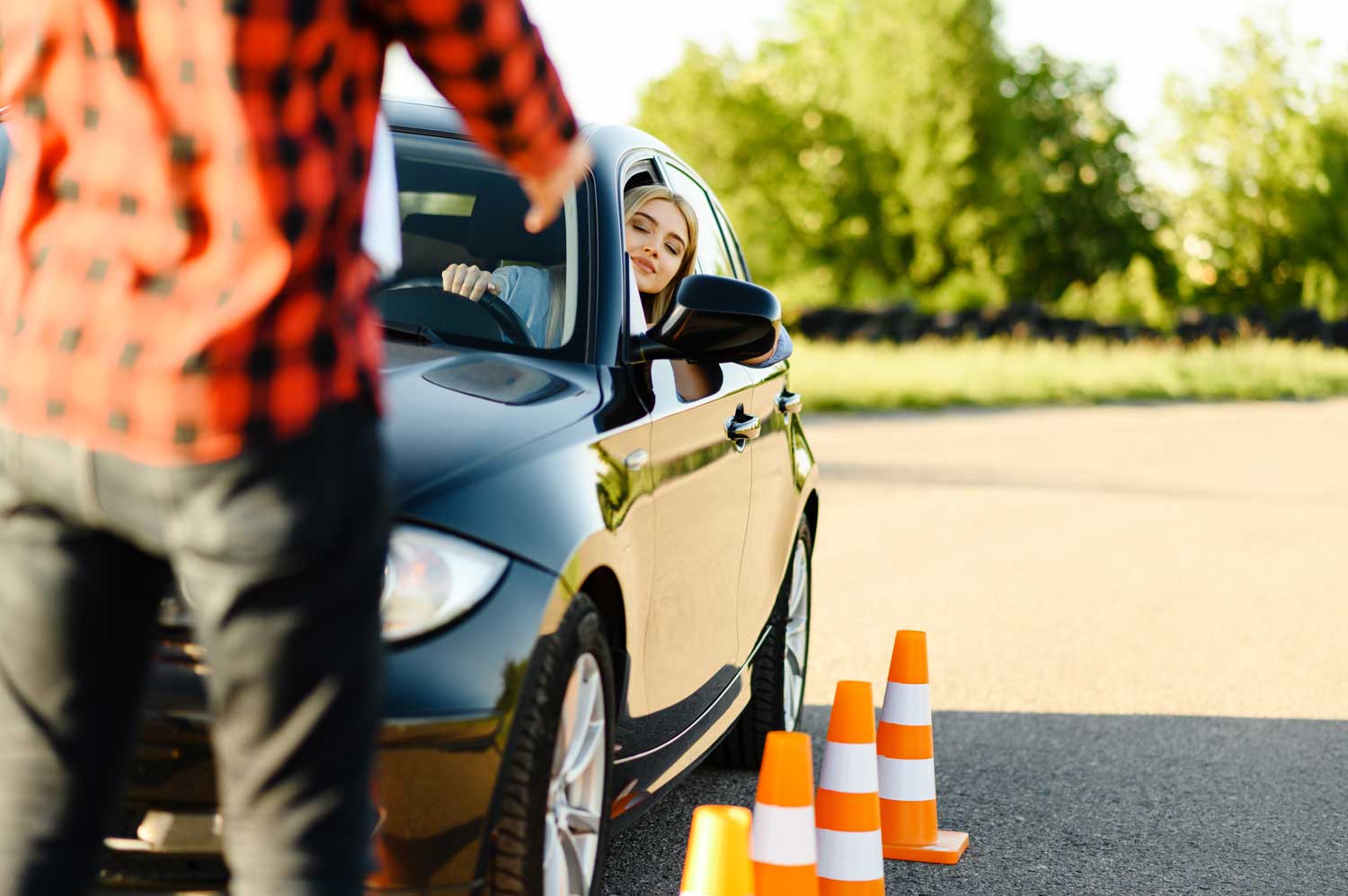 Smiling learner driver leaning out of a car window during a lesson