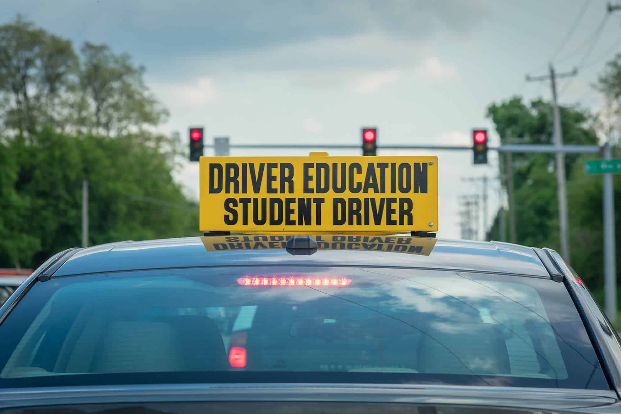 Car with a student driver sign stopped at a traffic light